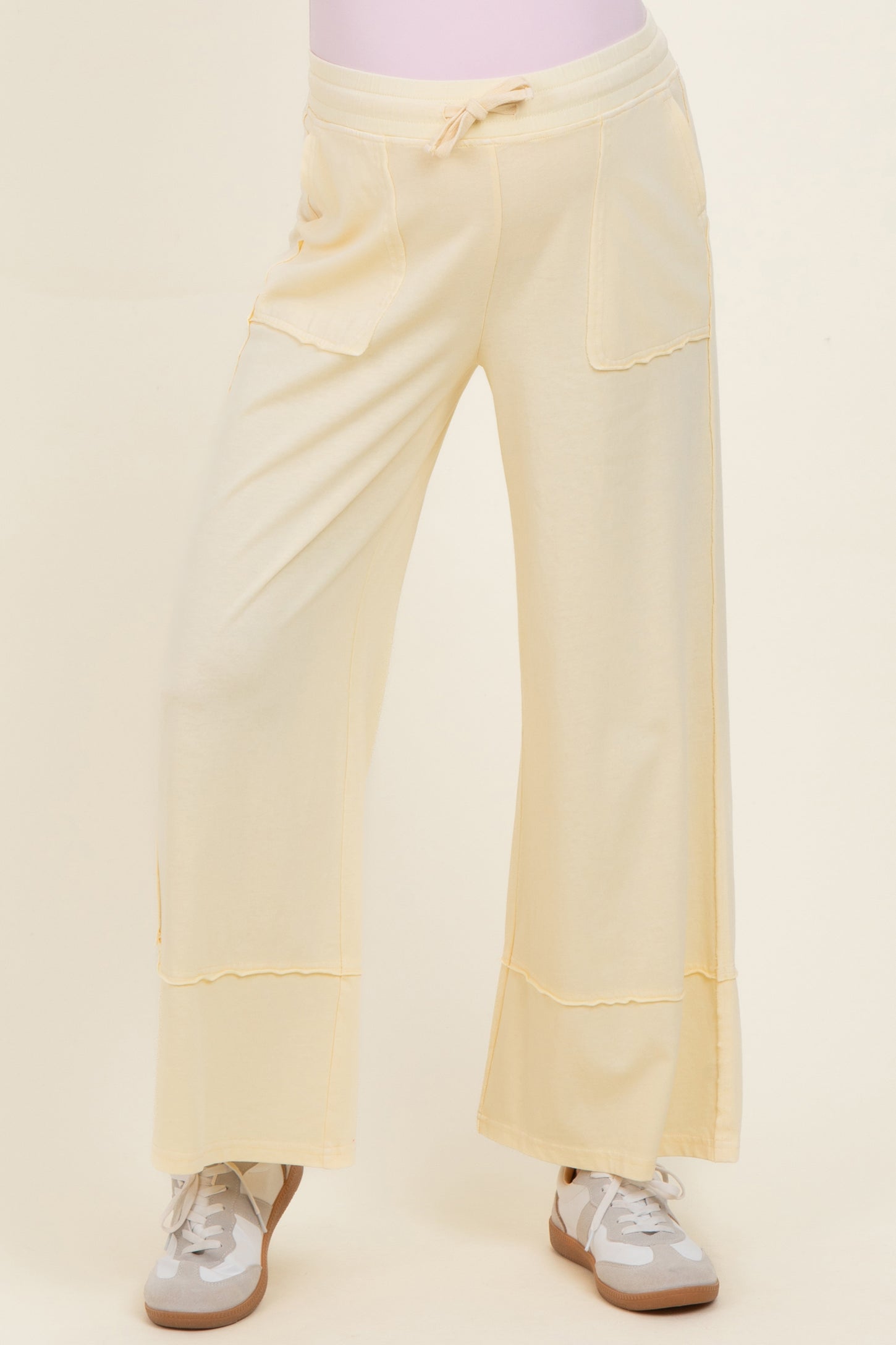 maternity wear in a soft yellow color featuring wide leg design and front pockets, styled with sneakers