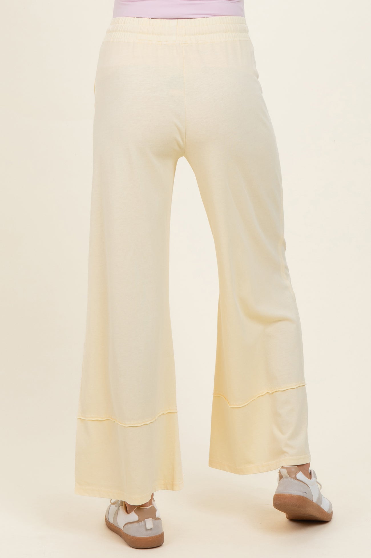 woman wearing light yellow maternity wide-leg pants, seen from the back