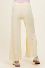 woman wearing light yellow maternity wide-leg pants, seen from the back