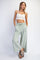woman wearing a white cropped tank top and light green wide-leg pants with pockets and a drawstring waist