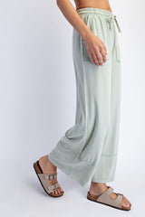 woman wearing light green wide-leg pants with side pockets and adjustable drawstring, paired with beige slide sandals