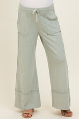 woman wearing light green maternity wide-leg pants with two front pockets and an elastic waistband