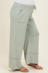 woman wearing light green maternity wide-leg pants with pockets and an elastic waistband, showing her baby bump
