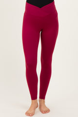 woman wearing high-waisted burgundy maternity leggings with a crossover waistband