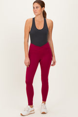 woman wearing a dark gray tank top and maroon high-waisted leggings with white sneakers