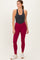 woman wearing a dark gray tank top and maroon high-waisted leggings with white sneakers