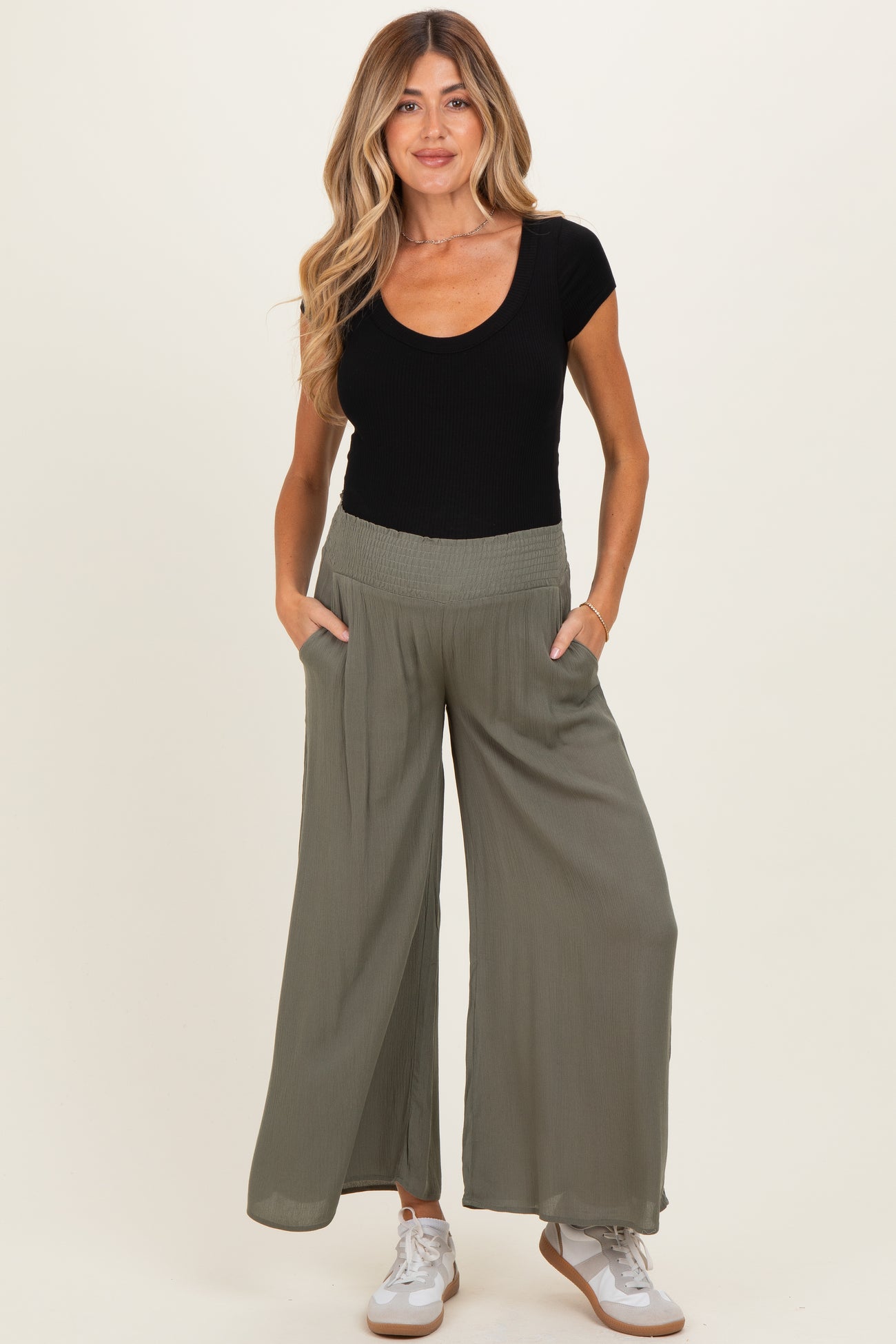 woman wearing a black ribbed scoop neck maternity top and olive green wide leg maternity pants with pockets