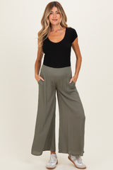 woman wearing a black ribbed scoop neck maternity top and olive green wide leg maternity pants with pockets
