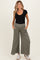 woman wearing a black ribbed scoop neck maternity top and olive green wide leg maternity pants with pockets