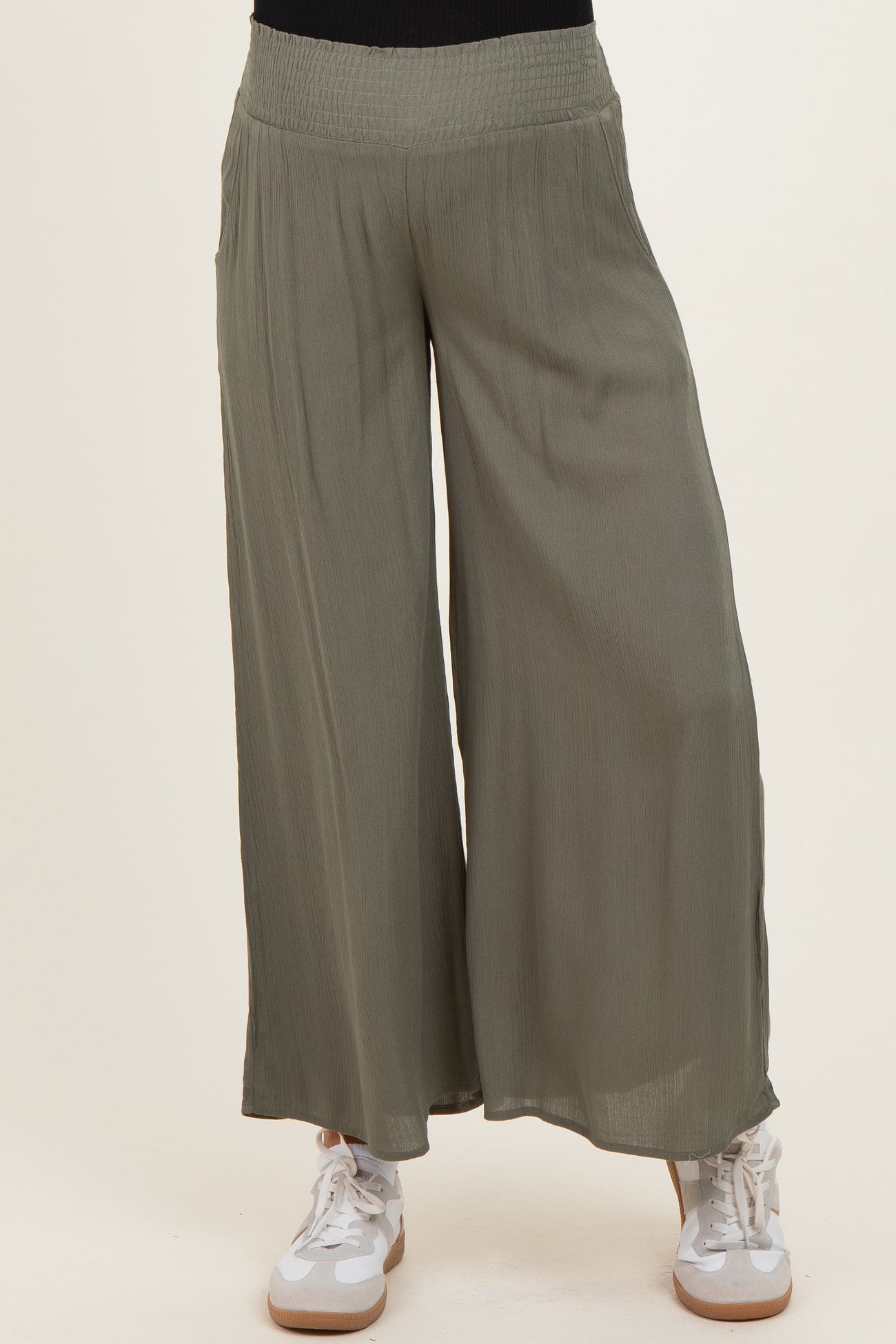 woman wearing olive green wide-leg maternity pants with a stretchy waistband and paired with white sneakers