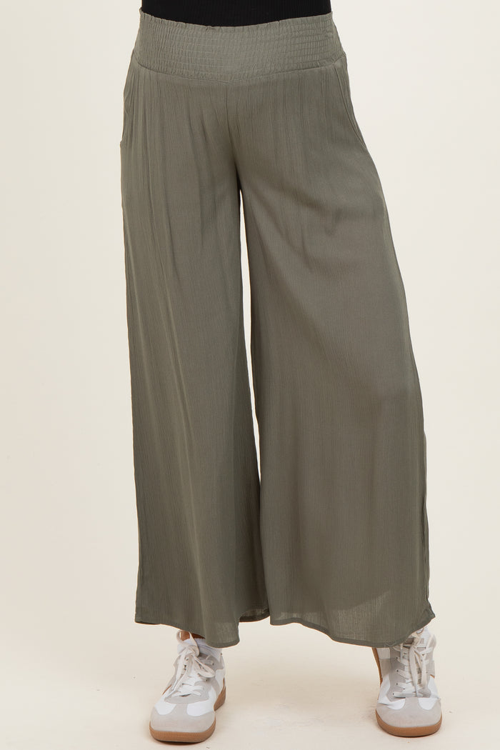 woman wearing olive green wide-leg maternity pants with a stretchy waistband and paired with white sneakers