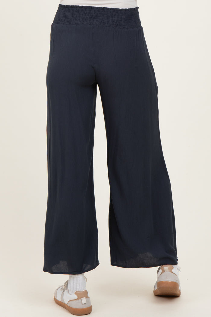 maternity wear navy blue wide leg pants with a smocked waistband, shown from the back, model wearing sandals