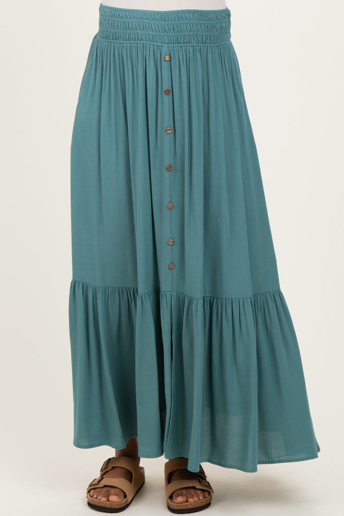 woman wearing a teal maternity skirt with buttons down the front and a tiered hem, styled with sandals