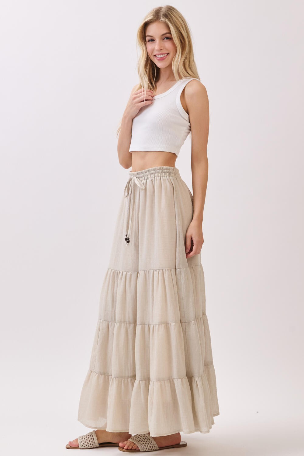 woman wearing a white crop top and a beige tiered maxi skirt with a drawstring waist