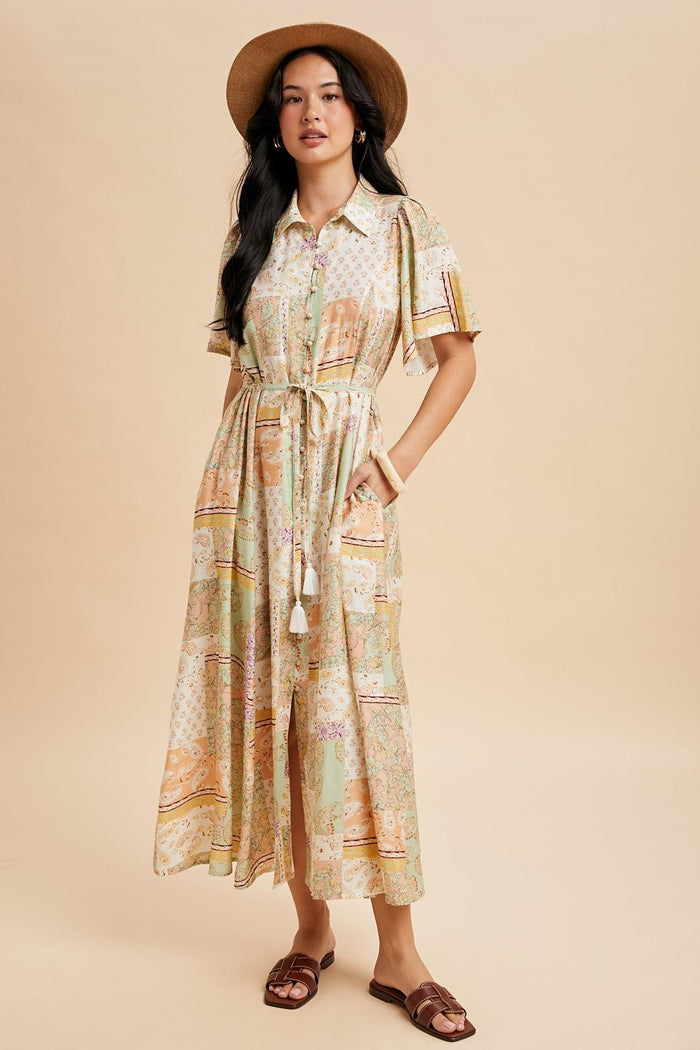 woman wearing a floral patterned maxi dress with short sleeves and a tie waist, paired with a wide-brimmed hat