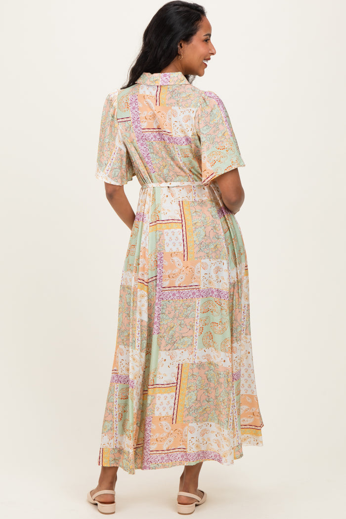 woman wearing a flowy pastel patterned maternity dress with short sleeves and a cinched waist, showing her baby bump