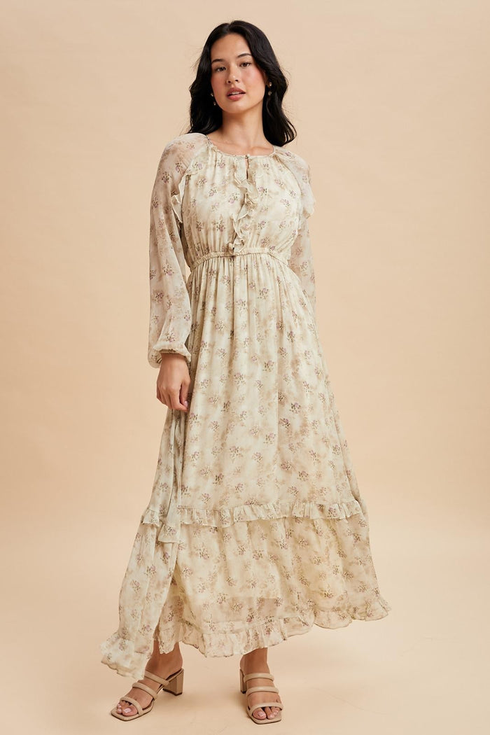woman wearing a cream floral maxi dress with long sleeves and ruffled hem details