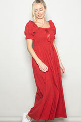 woman wearing a red long puff sleeve maxi dress with a square neckline and smocked bodice, paired with white sneakers