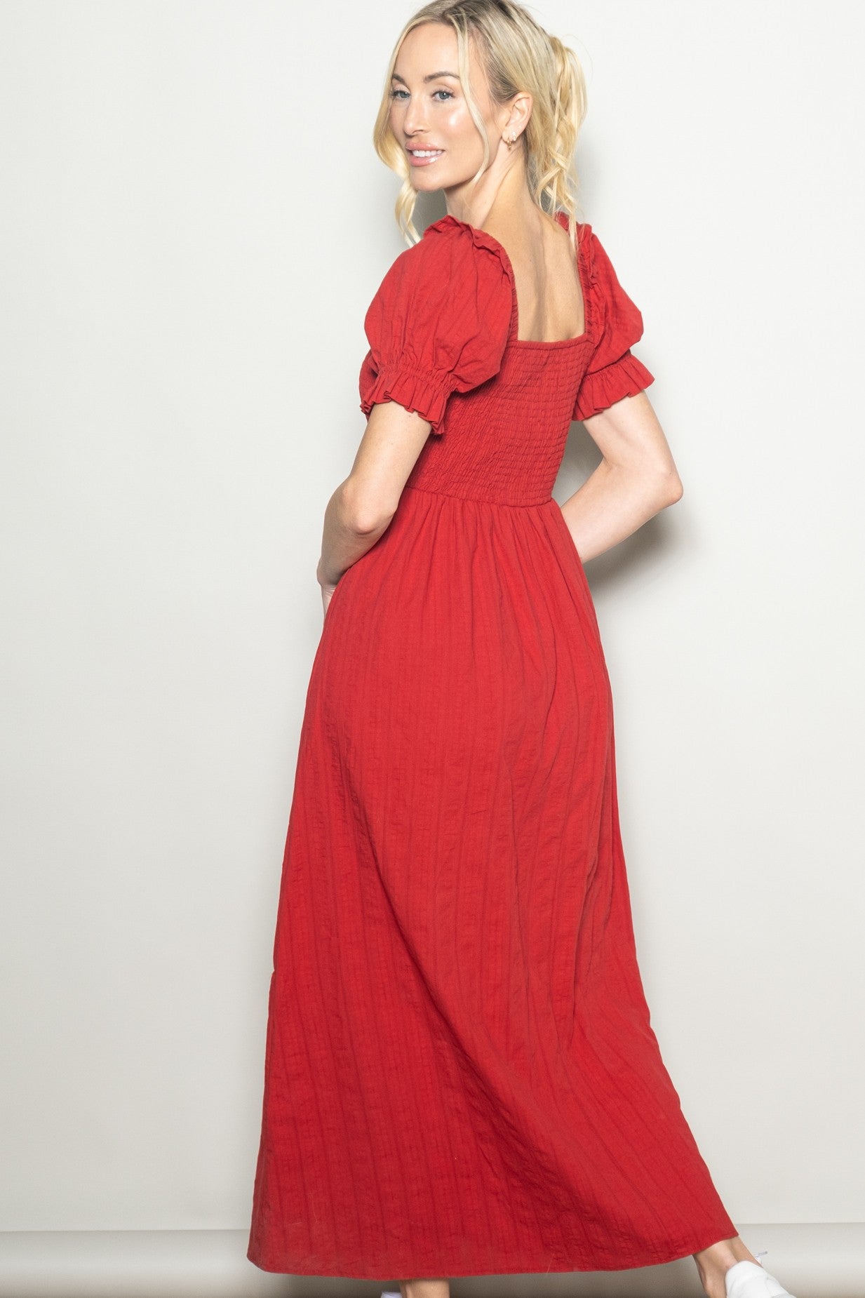 woman wearing a red puff sleeve maxi dress with a square neckline and smocked bodice, shown from the back