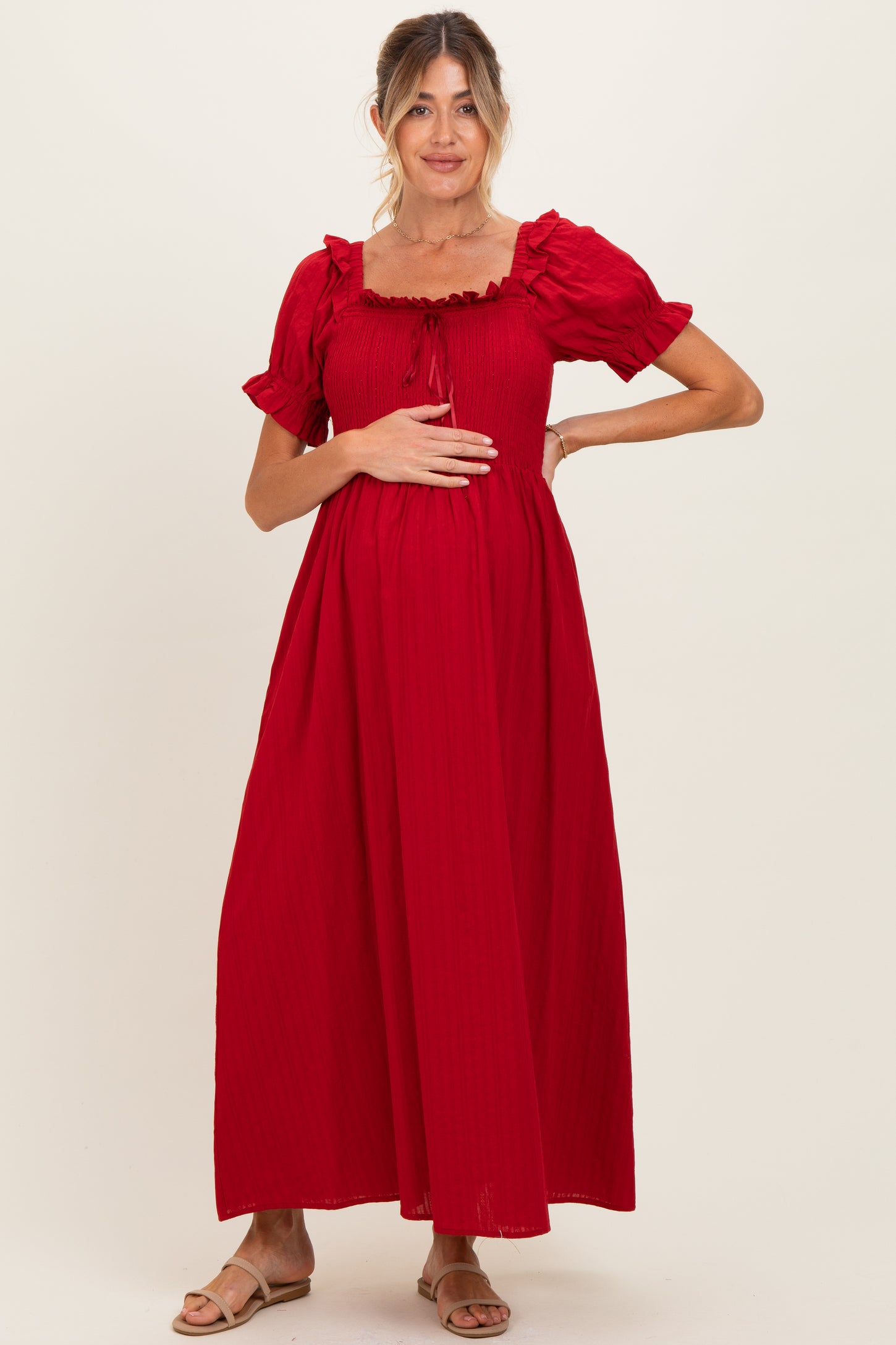 woman wearing a red ribbed maternity maxi dress with short puff sleeves and holding her baby bump