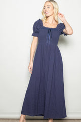 woman wearing a navy blue puff sleeve maxi dress with a square neckline and tie detail