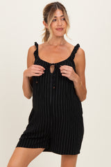woman wearing a black striped maternity romper with ruffle straps and a tie front detail