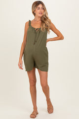 woman wearing an olive green striped maternity romper with ruffle straps and a tie detail, showing her baby bump