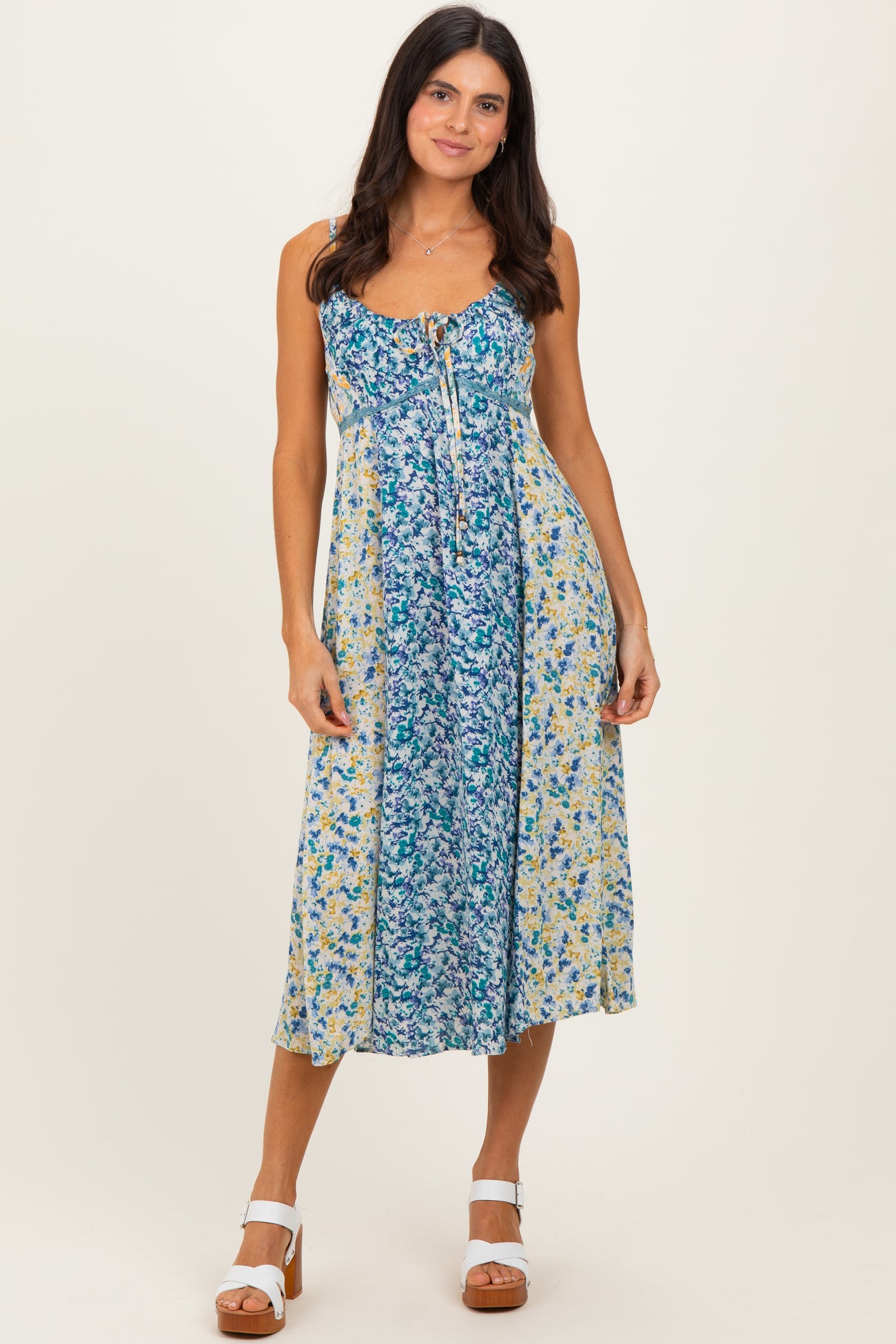 woman wearing a floral blue and yellow midi dress with a scoop neckline and adjustable straps