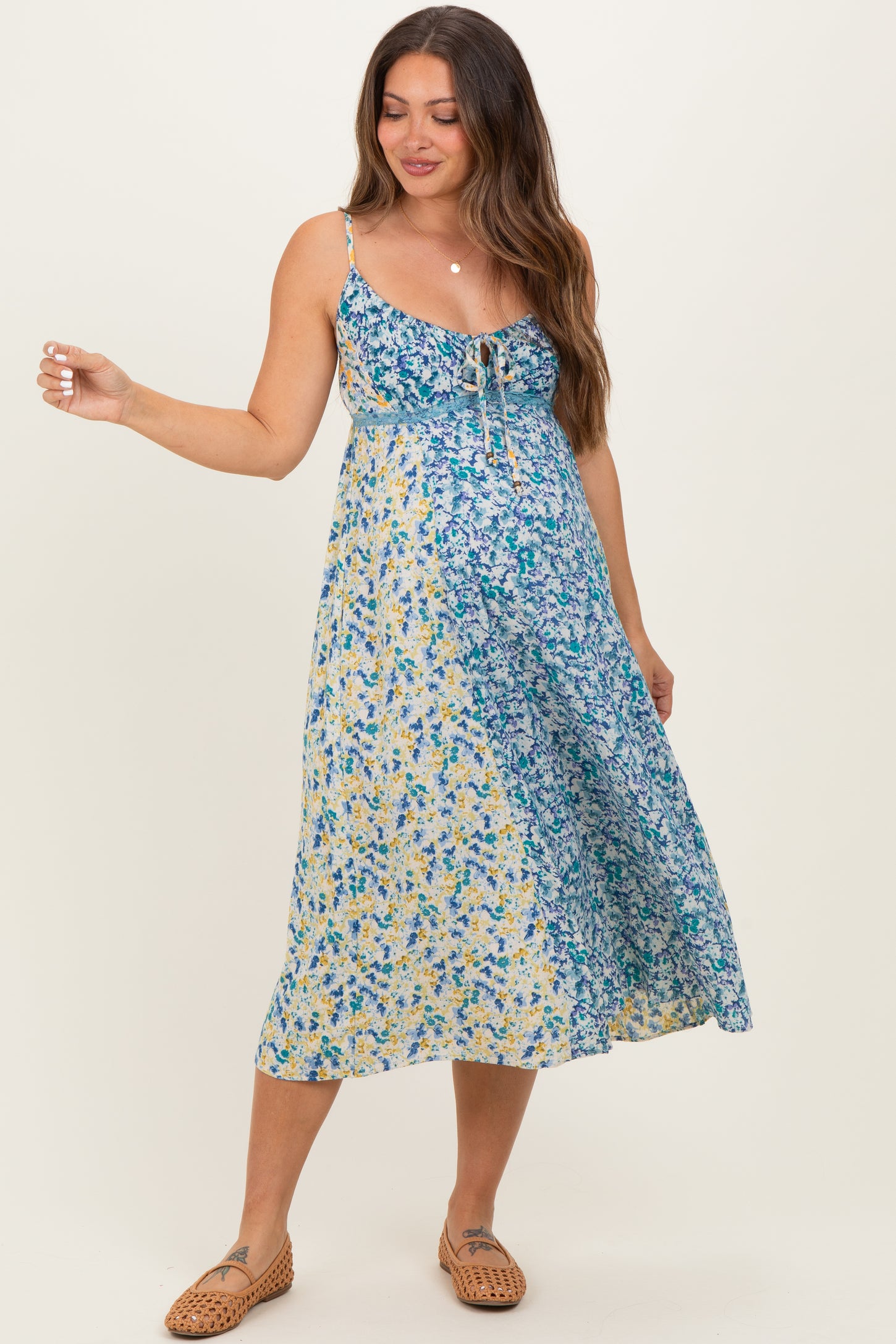 woman wearing a floral maternity dress with a mixed pattern in blue and yellow, showcasing her baby bump