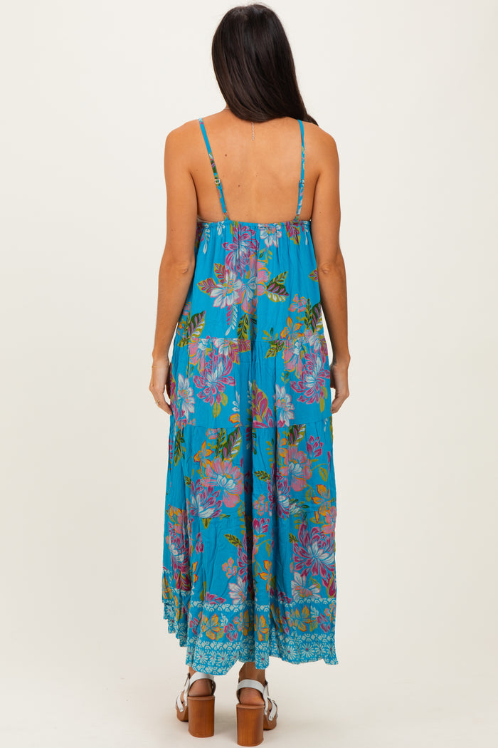 woman wearing a turquoise floral maxi dress with spaghetti straps, seen from the back