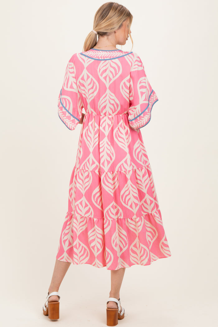 woman wearing a pink leaf print midi dress with tiered ruffles and short sleeves, shown from the back
