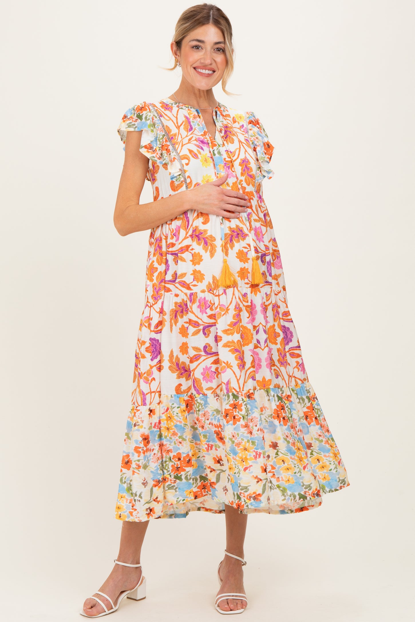 woman wearing a floral print maxi maternity dress with ruffle sleeves and a visible baby bump