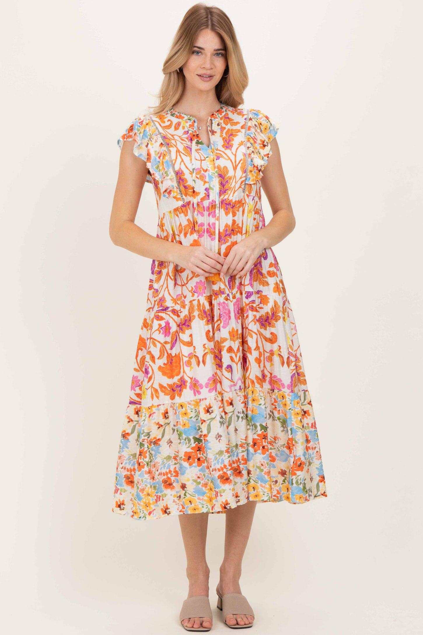 woman wearing a colorful floral midi dress with ruffled sleeves and a tiered skirt