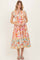 woman wearing a colorful floral midi dress with ruffled sleeves and a tiered skirt