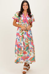 woman wearing a colorful floral maxi dress with short sleeves and a v-neckline, standing against a light background