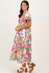 woman wearing a colorful floral maxi dress with ruffled sleeves and tiered skirt, standing sideways