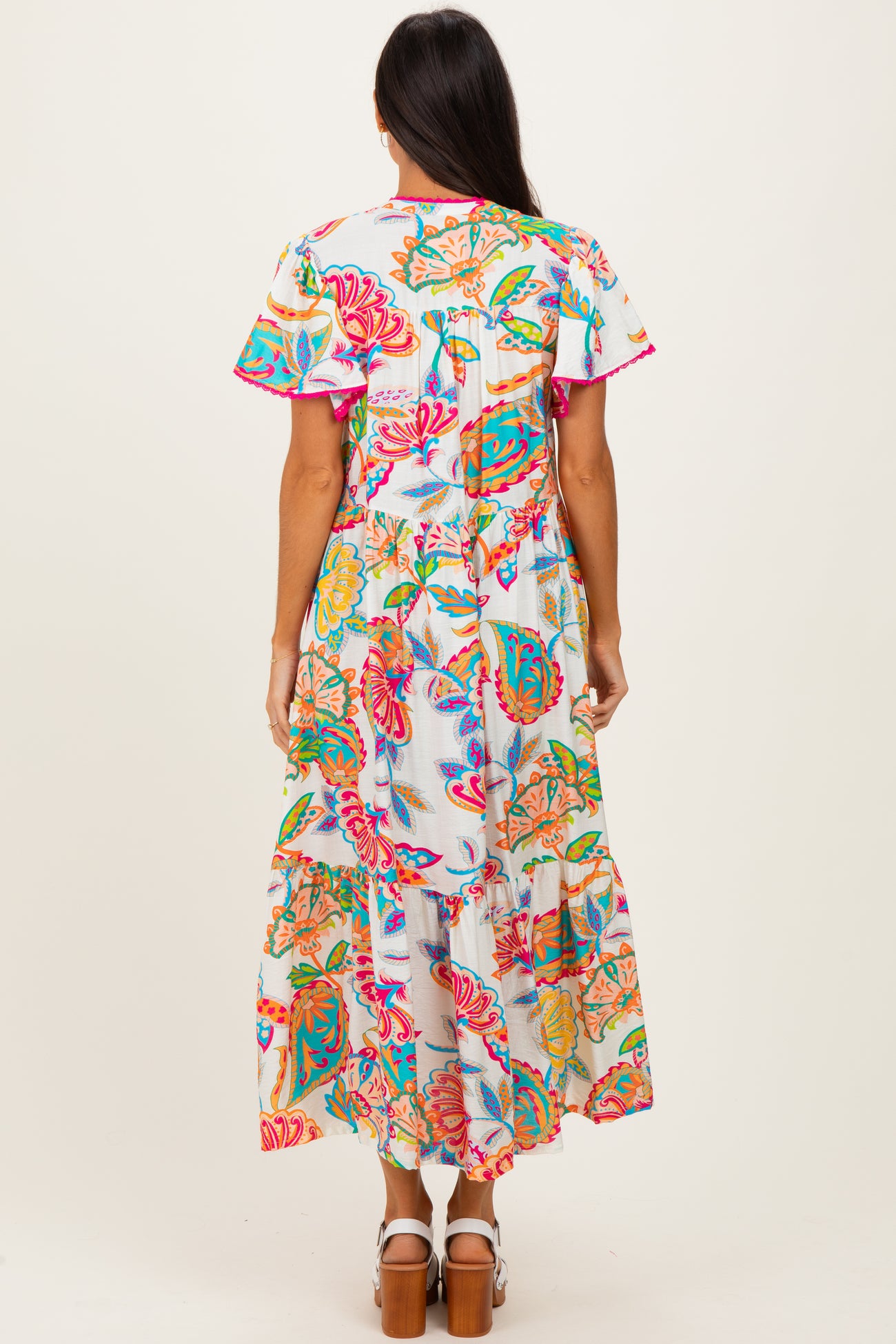woman wearing a colorful floral maxi dress with short sleeves and a tiered skirt from the back