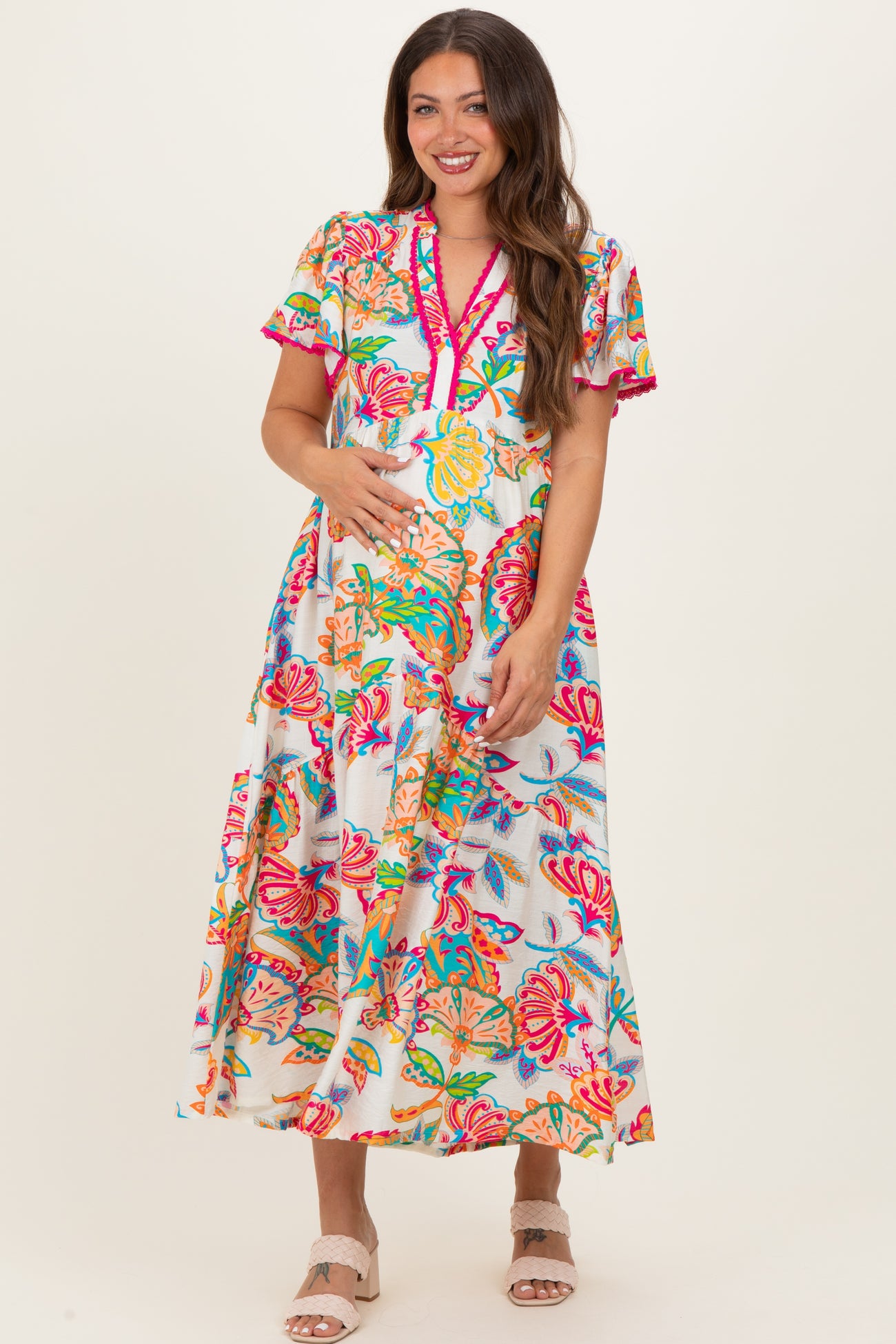 woman wearing a colorful floral maternity maxi dress with short sleeves and a baby bump visible