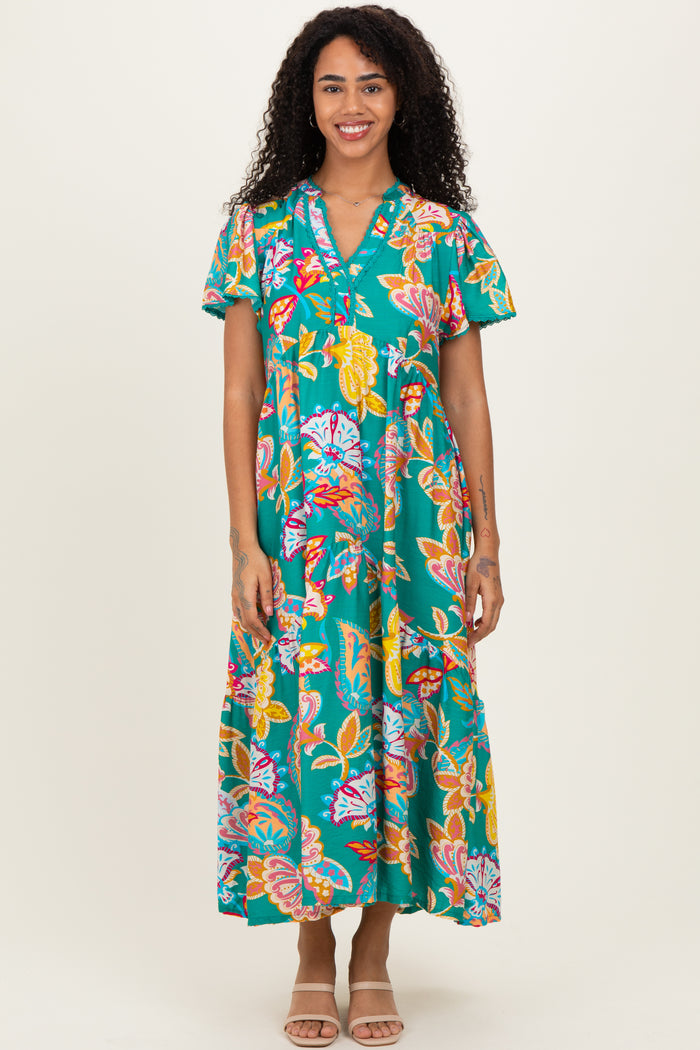 woman wearing a teal floral maxi dress with short sleeves and a button-up neckline
