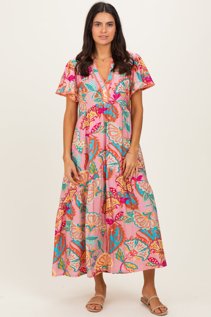 woman wearing a pink floral maxi dress with short flutter sleeves and v-neckline