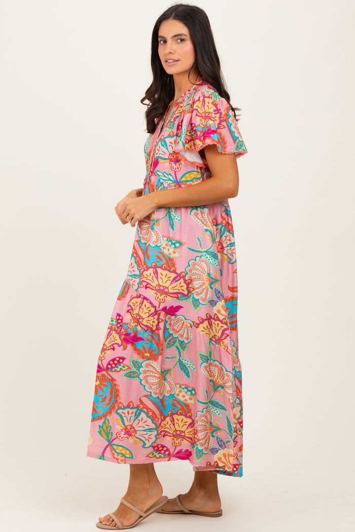 woman wearing a pink floral maxi dress with flutter sleeves and vibrant patterns