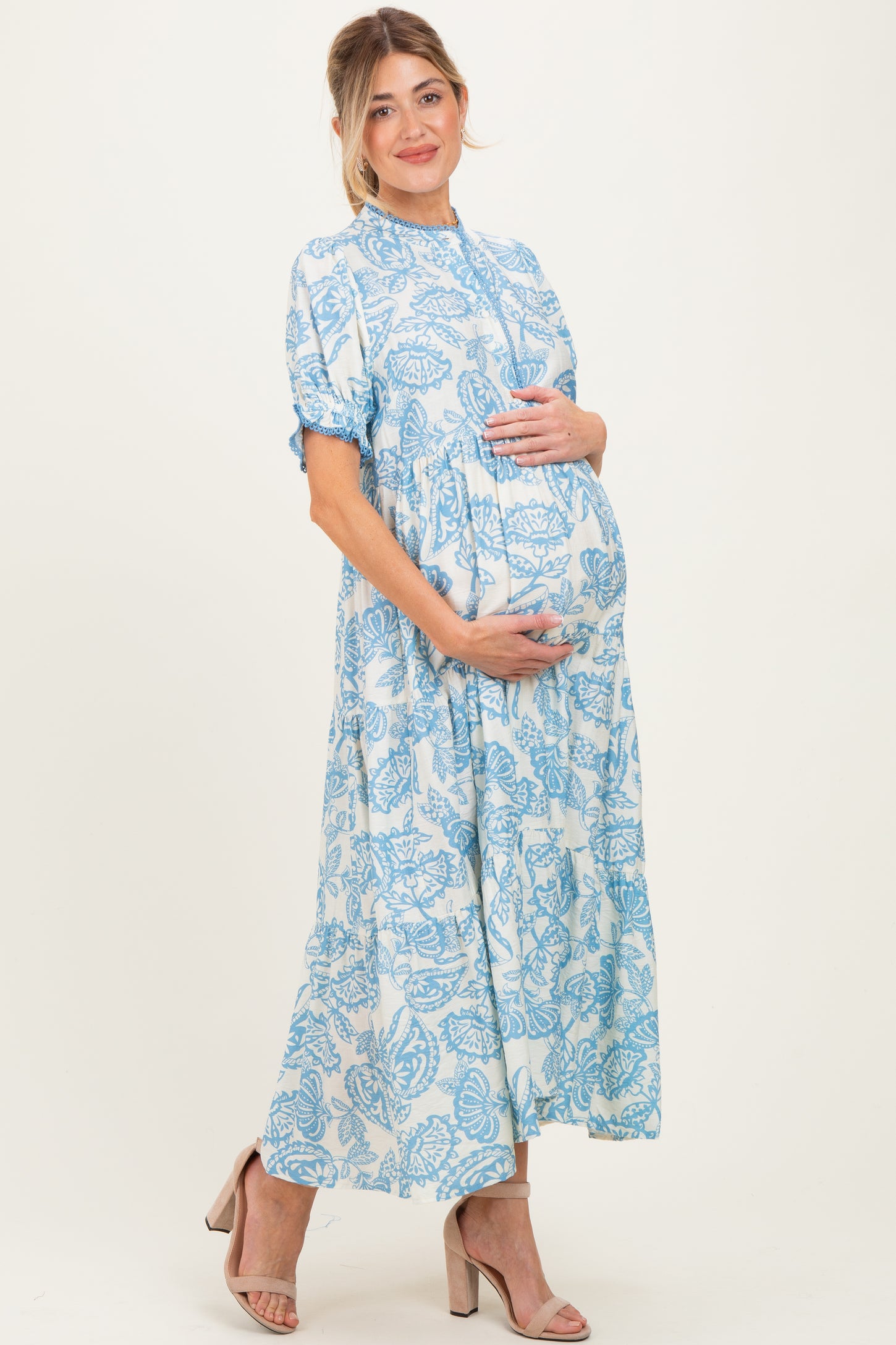 woman wearing a light blue floral maternity maxi dress and holding her baby bump