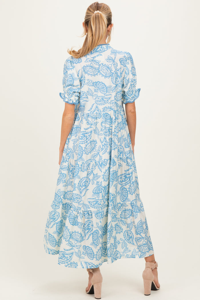 woman wearing a blue floral print maternity maxi dress with short sleeves and a flowy skirt