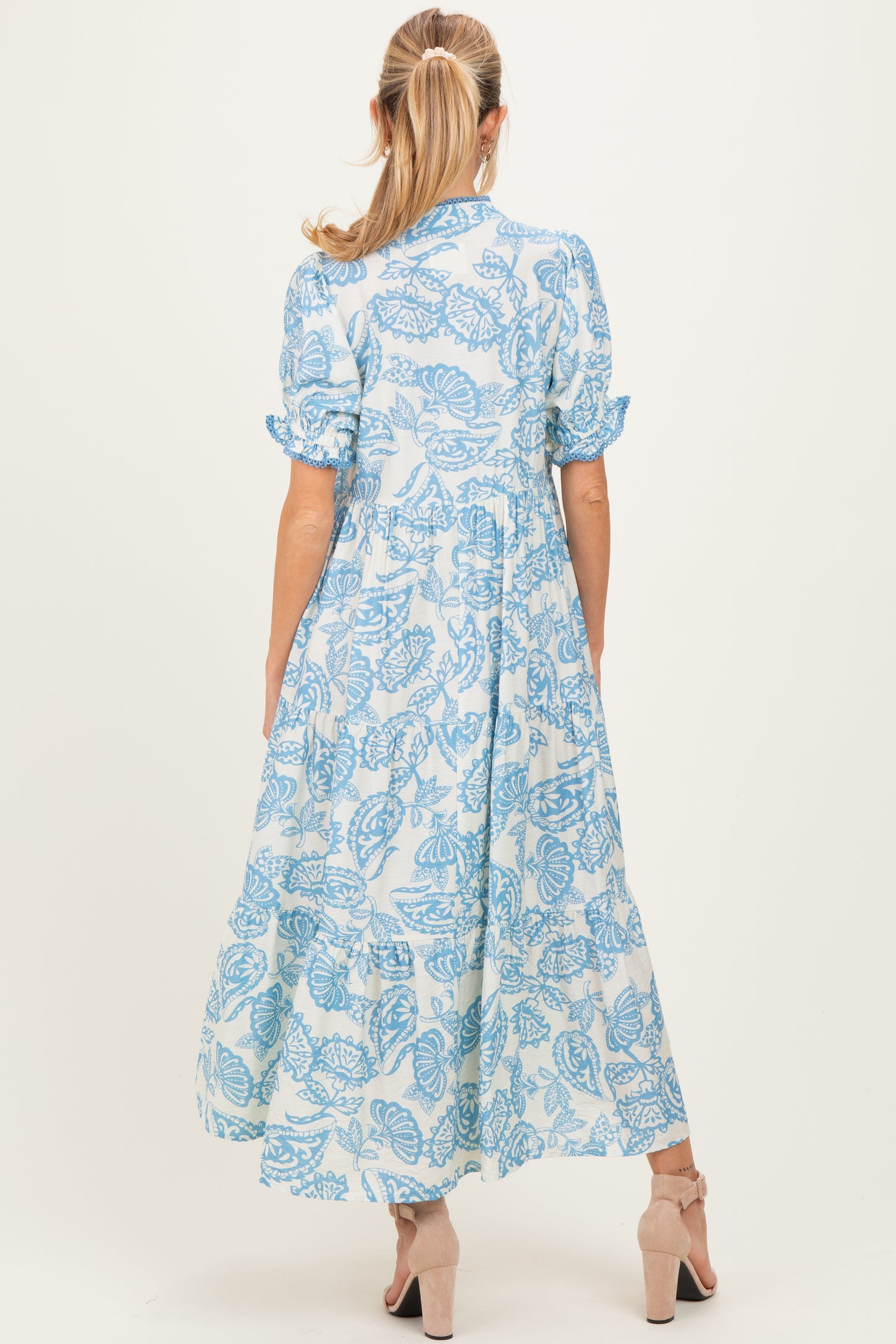 woman wearing a blue floral print maternity maxi dress with short sleeves and a flowy skirt