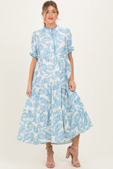 woman wearing a blue and white floral print maternity dress with a tiered skirt and short puff sleeves