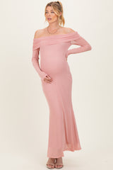 woman wearing a dusty rose off-shoulder maternity gown with long sleeves and a fitted silhouette, showing baby bump