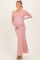 woman wearing a dusty rose off-shoulder maternity gown with long sleeves and a fitted silhouette, showing baby bump