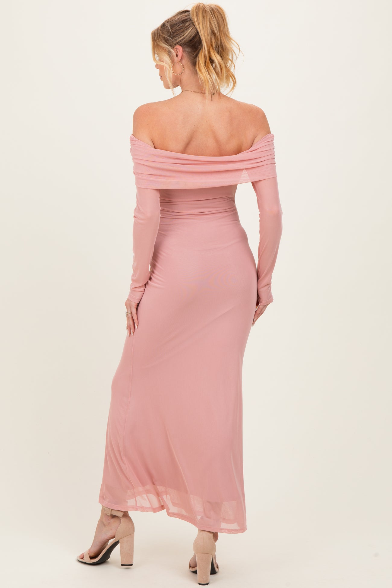 woman wearing a blush pink off-the-shoulder maternity dress with long sleeves and a fitted silhouette