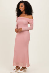 woman wearing a dusty pink off-the-shoulder maxi dress with long sleeves and a fitted silhouette