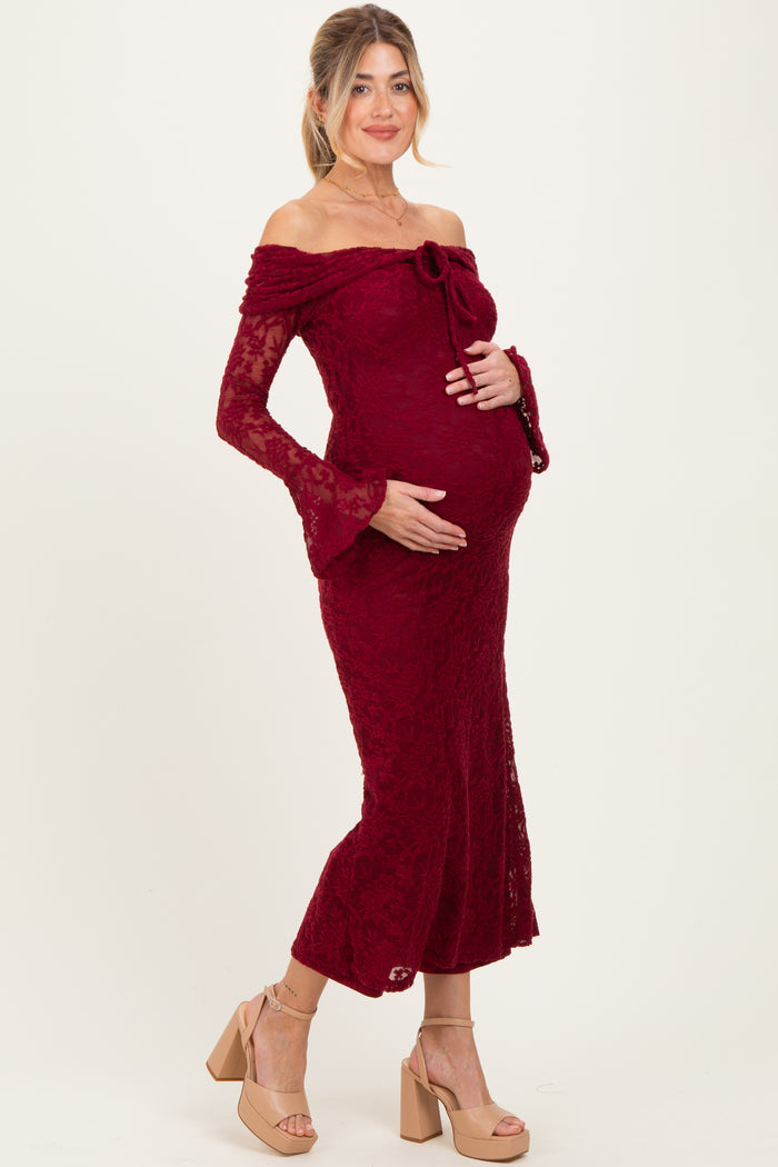 woman wearing a burgundy lace off-the-shoulder maternity gown and holding her baby bump